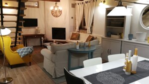 A cozy living room with a sofa, a yellow armchair, a dining table with a placemat, and a TV mounted on the wall. - Cute vacation house surrounded by green area (Buzet)