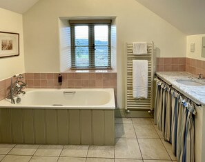 Ein Badezimmer mit einer Badewanne, einem Fenster, einem Handtuchhalter und einer Dusche.