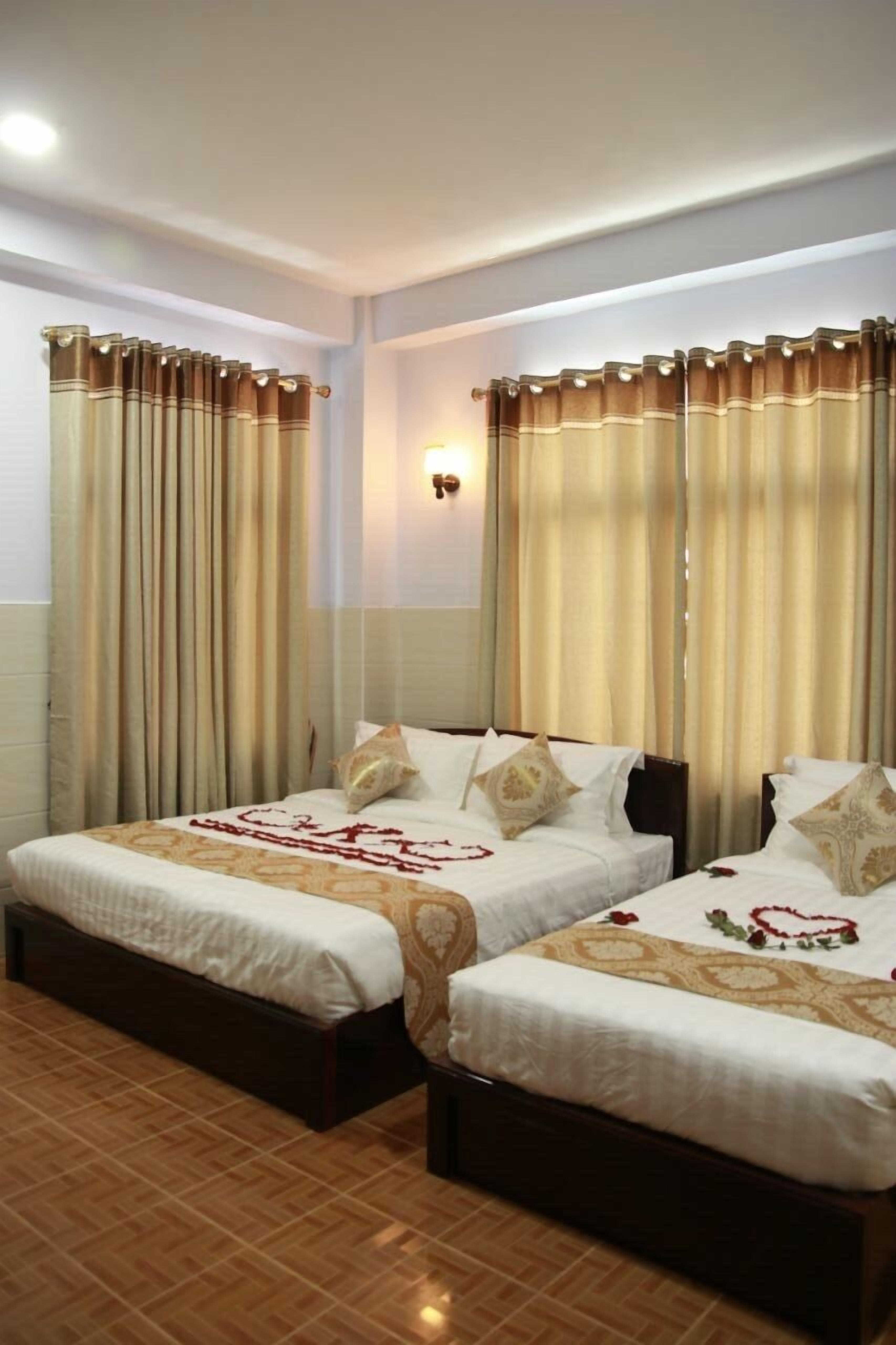 A hotel room with two beds, a wall-mounted light, and curtains.