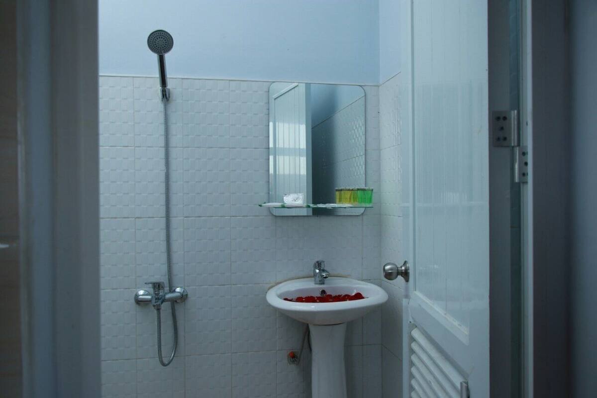 Une salle de bain avec une douche, un lavabo décoré de pétales de rose et un miroir au-dessus du lavabo.