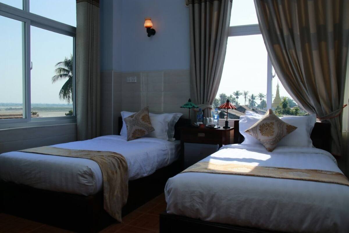 Une chambre d’hôtel avec deux lits, une table de chevet, une lampe et une vue sur la plage et le temple.