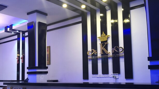 A reception desk with a modern design, featuring a prominent "King Hotel" sign and a decorative emblem above it. - King Hotel (Katha)