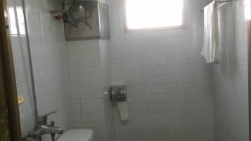 A small, compact bathroom with a toilet, bidet, and sink. There is a window providing natural light and a towel rack above the toilet.