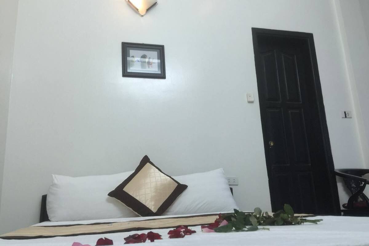 Una habitación de hotel con una cama, un cuadro en la pared y una puerta.