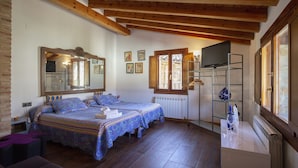 Un dormitorio con dos camas, un espejo grande, vigas de madera, un televisor y una ventana.