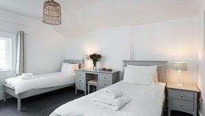Ett hotellrum med två sängar, ett skrivbord, en stol, en bordslampa och en hängande taklampa.