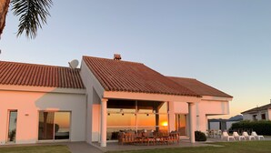 A modern house with a tiled roof, a covered patio with outdoor furniture, and a view of the sunset. - Magnificent luxury villa for 10 to 16 people. - magnificent sea and mountain views (Manilva)