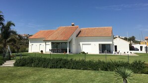 A modern two-story house with a red-tiled roof, a covered patio, and a well-maintained lawn. - Magnificent luxury villa for 10 to 16 people. - magnificent sea and mountain views (Manilva)