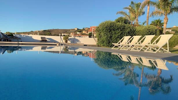 A clear pool with lounge chairs and a view of buildings in the background. - Magnificent luxury villa for 10 to 16 people. - magnificent sea and mountain views (Manilva)
