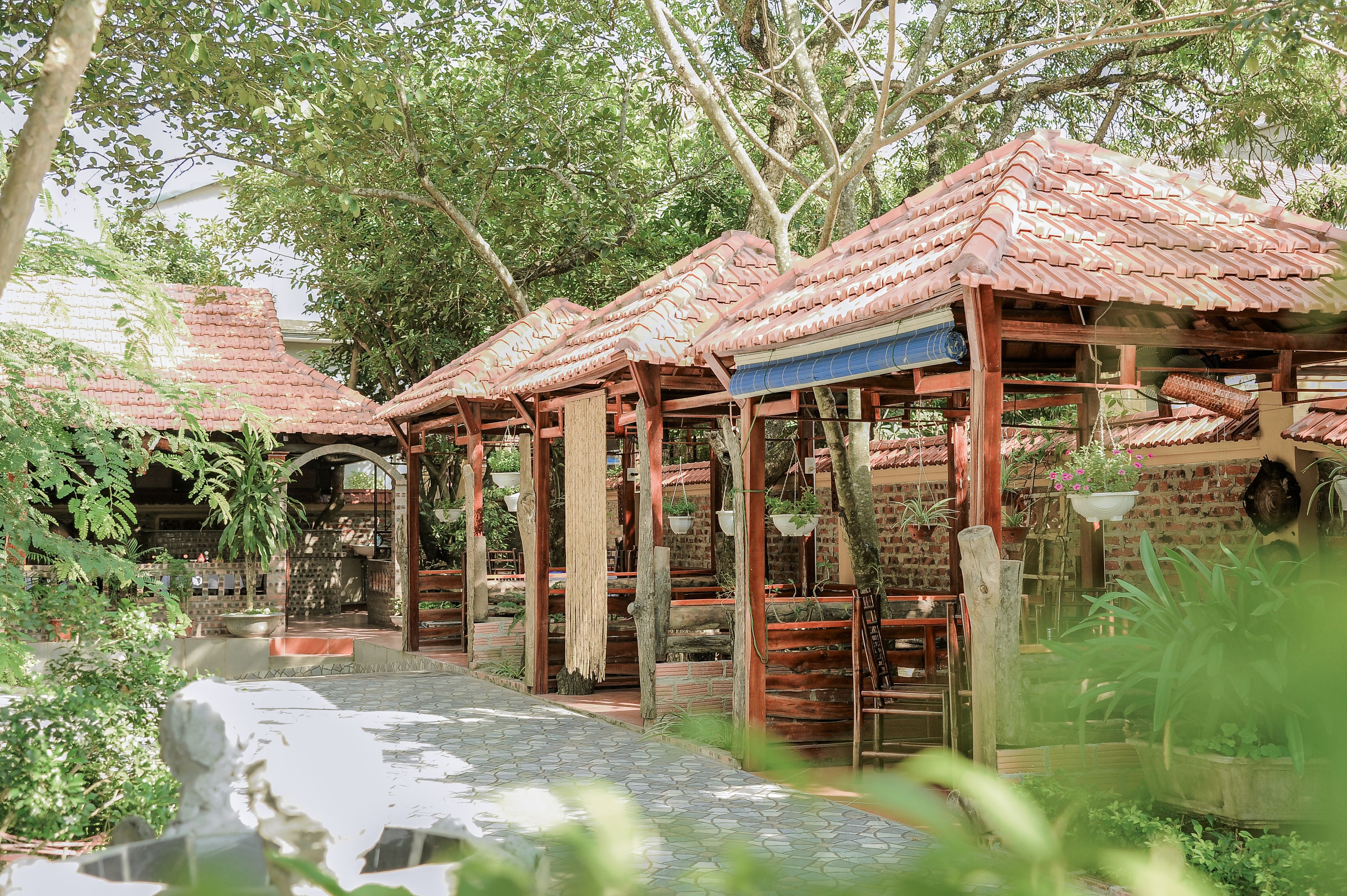 A traditional-style building with a tiled roof and wooden beams, surrounded by lush greenery and a stone pathway.