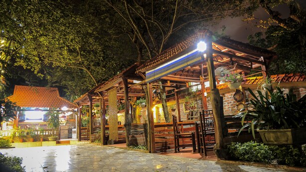 A covered outdoor area with a tiled floor, wooden benches, and potted plants. - Hoang Giang Homestay (Ninh Binh)
