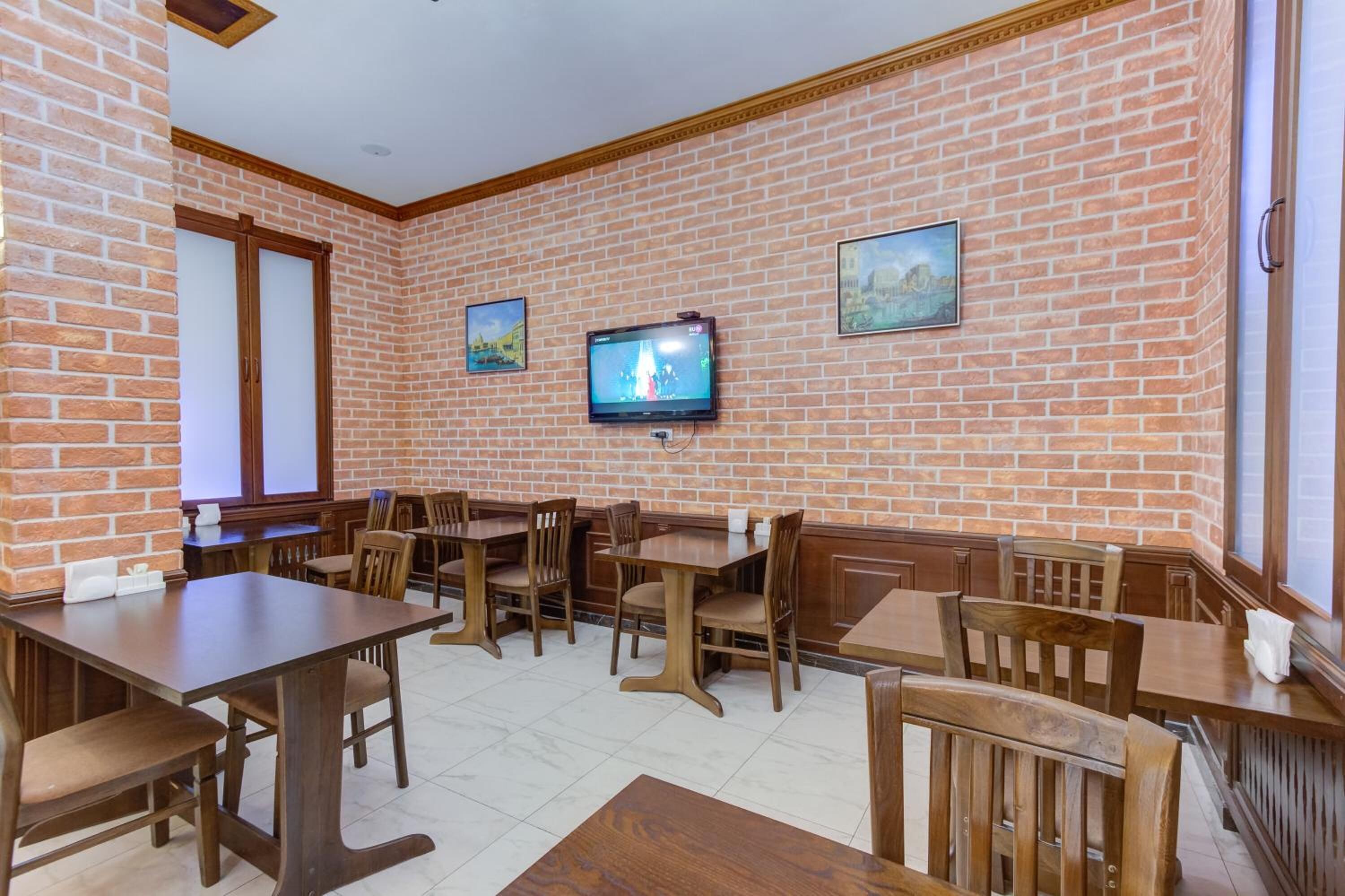 Un restaurante con paredes de ladrillo, mesas y sillas de madera, un televisor de pantalla plana en la pared y fotografías enmarcadas.