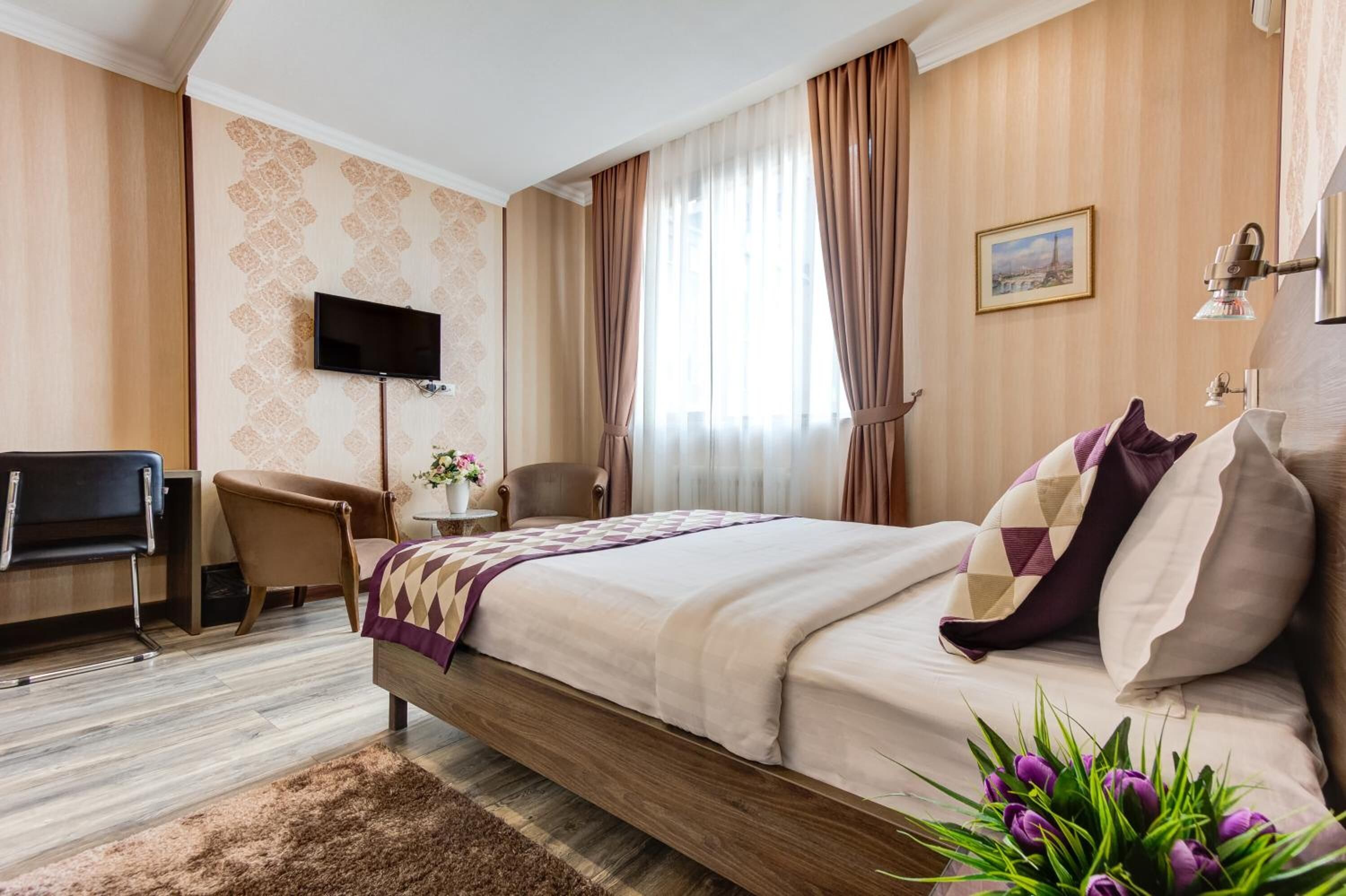 A hotel room with a bed, a TV, a desk, and a chair.