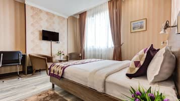 A hotel room with a bed, a TV, a desk, and a chair.