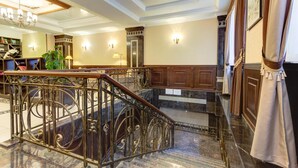 A grand lobby with marble flooring, a wrought iron staircase, and a chandelier. - Bishkek Centrum Hotel (Bishkek)