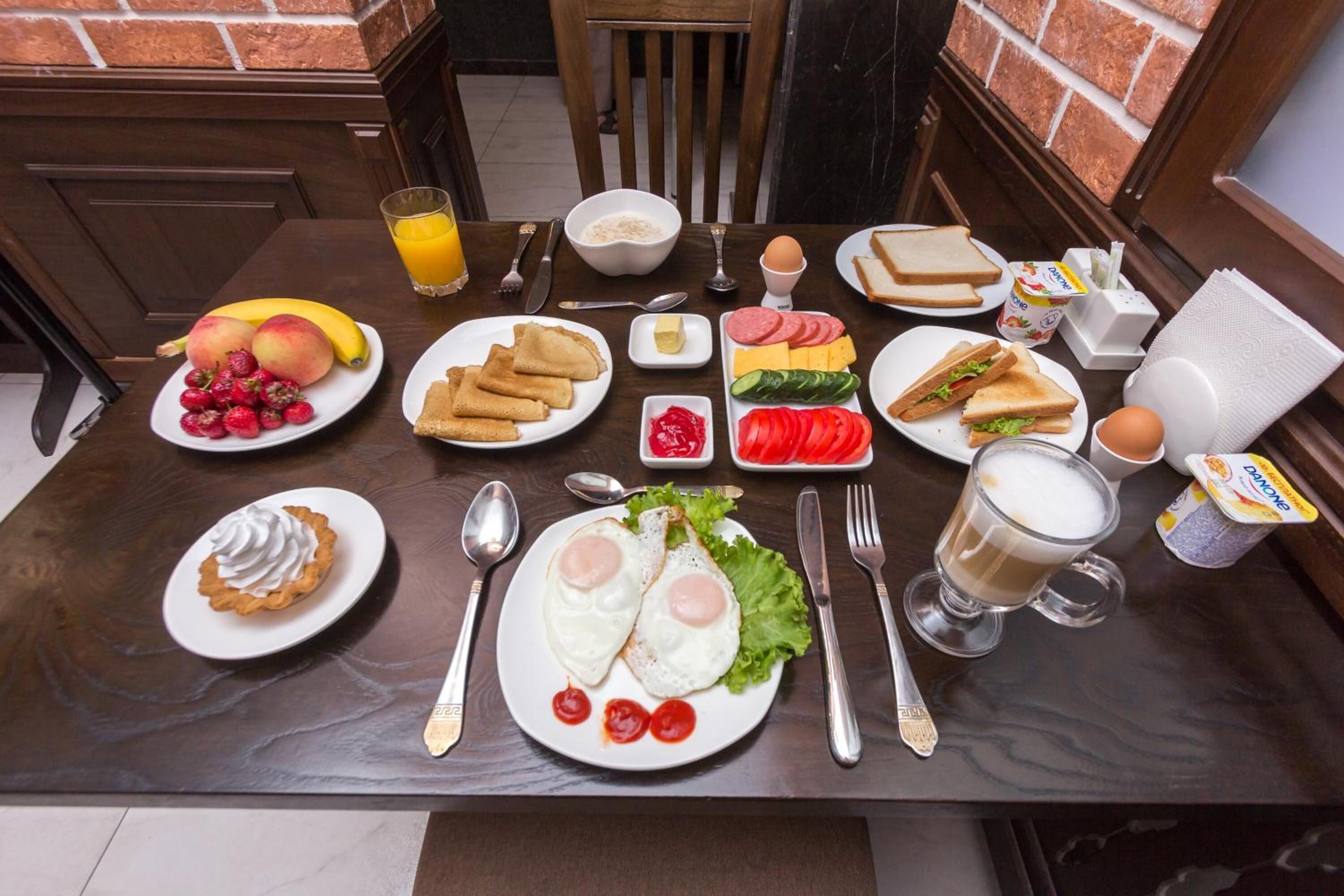 A breakfast table with plates of eggs, toast, fruit, and beverages.