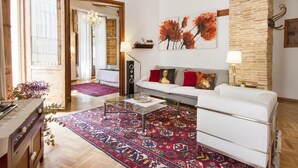 Un salon avec un canapé blanc, un tapis à motifs et un grand tableau abstrait.