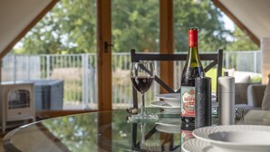 A dining table with a bottle of wine, a glass, and a bottle of champagne. - Miller's Loft, A romantic retreat for 2 (Erpingham)