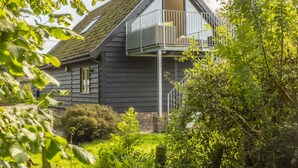 A dark-colored house with a balcony, surrounded by greenery. - Miller's Loft, A romantic retreat for 2 (Erpingham)