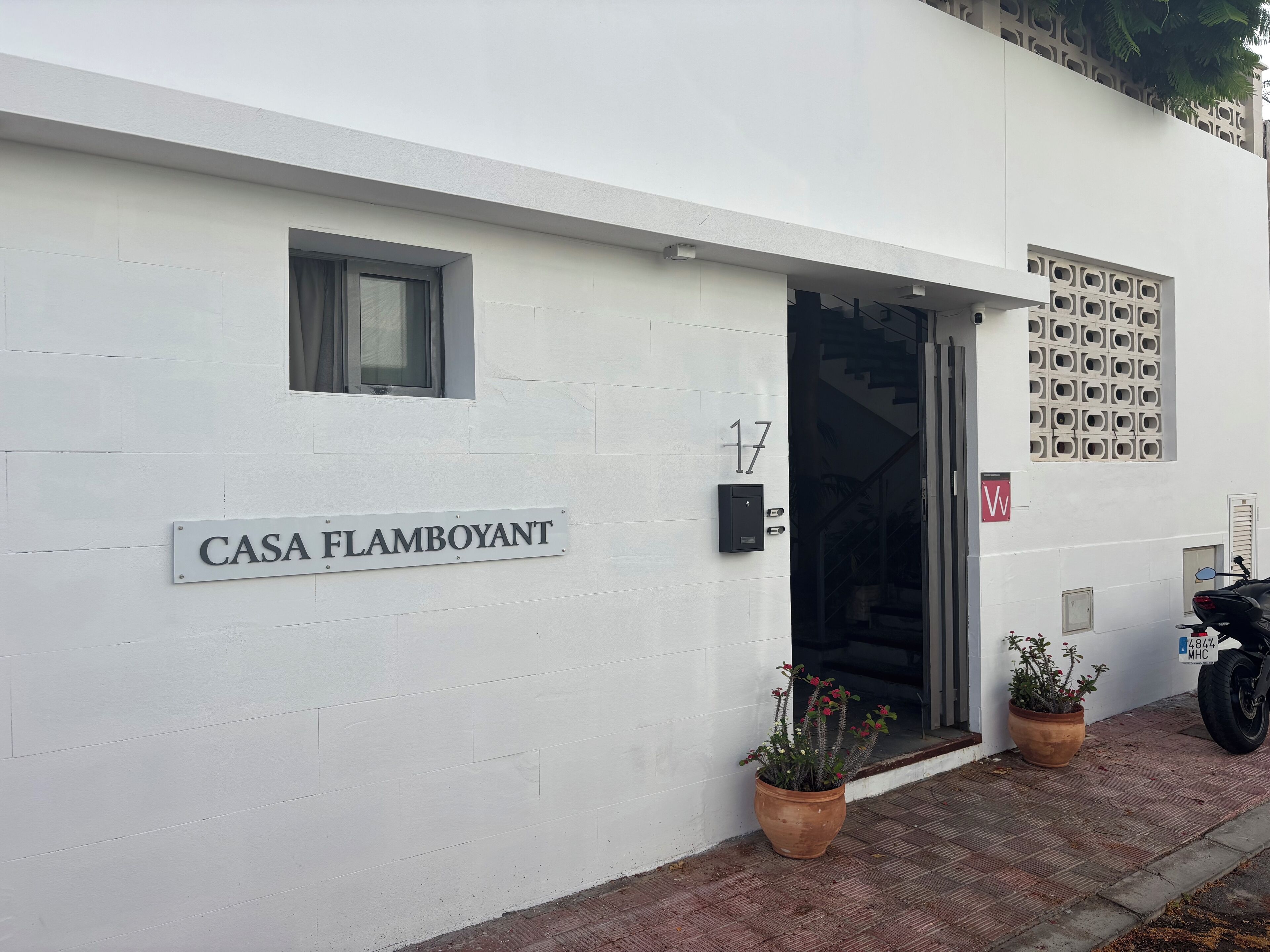 A white building with a sign reading "CASA FLAMBOYANT" and a number "17" above the entrance.