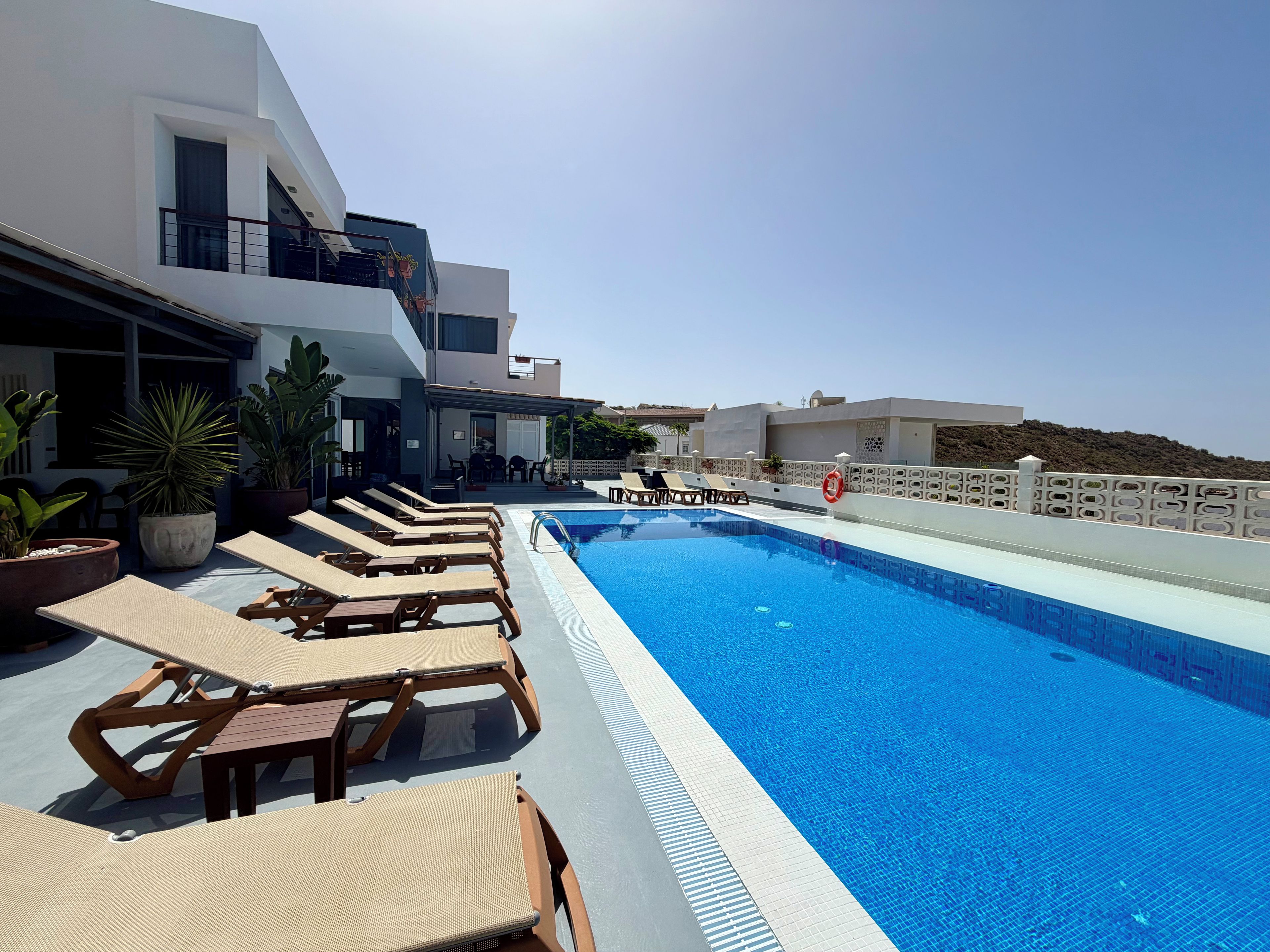 A pool area with lounge chairs and potted plants.