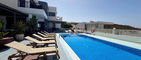A pool area with lounge chairs and potted plants.