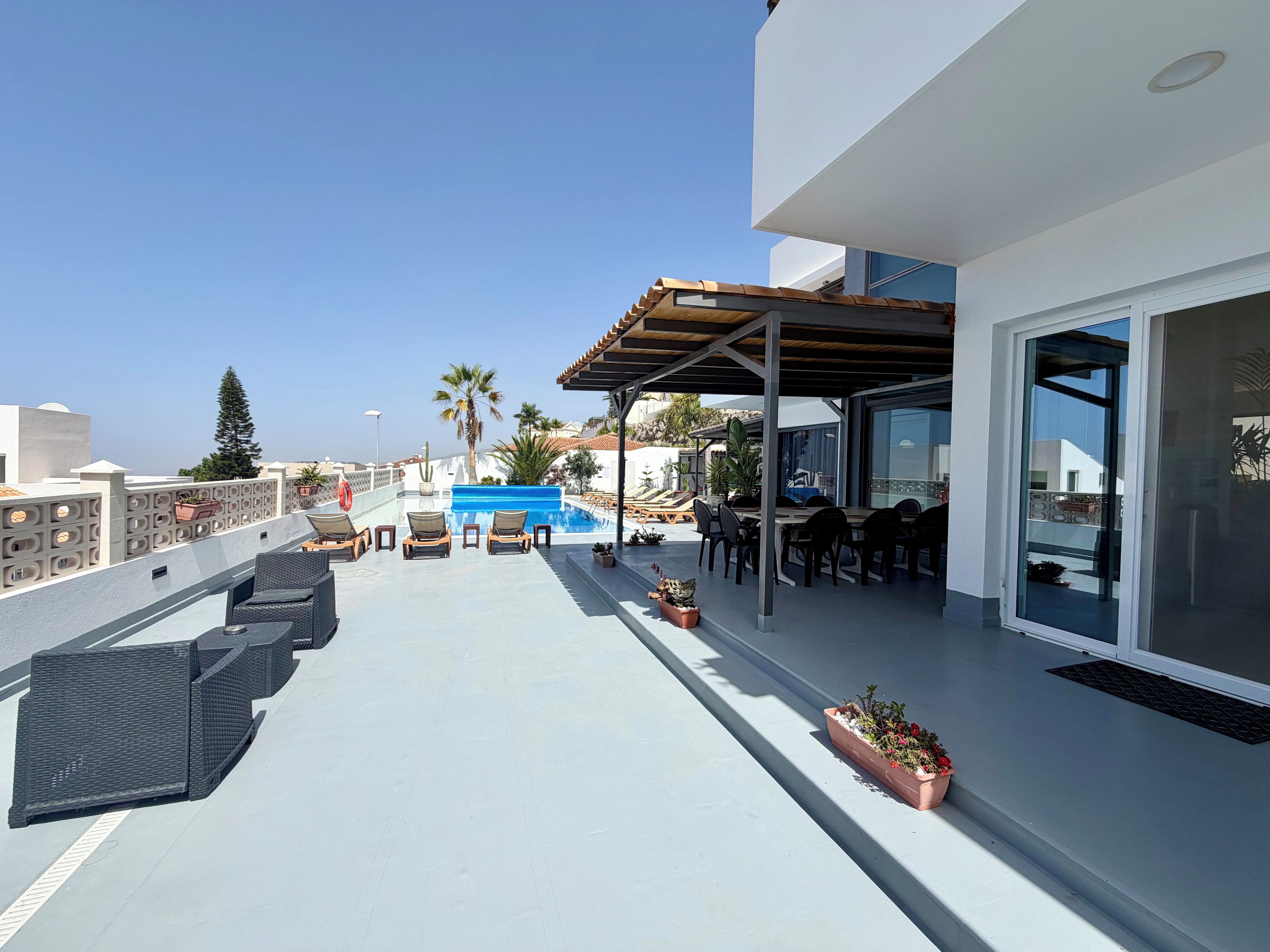 A rooftop terrace with a pool, lounge chairs, and a dining area.