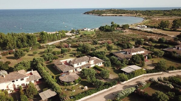 A coastal residential area with houses, a curved coastline, and a clear view of the sea.