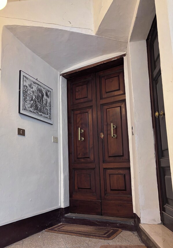 A dark wooden double door with brass handles, a framed black and white artwork on the adjacent wall, and a doormat at the entrance. - TOP-ROOF LARGE APARTMENT IN SPOLETO CITY CENTER, QUIET AND COZY TO FEEL AT HOME (Spoleto)