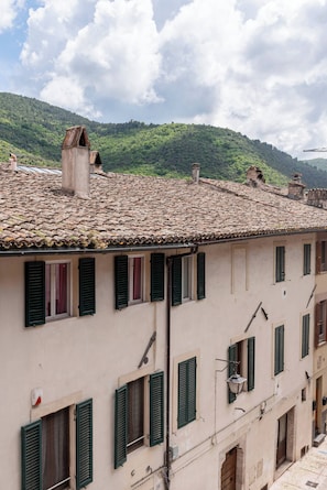 A building with multiple windows, green shutters, and a tiled roof. - TOP-ROOF LARGE APARTMENT IN SPOLETO CITY CENTER, QUIET AND COZY TO FEEL AT HOME (Spoleto)