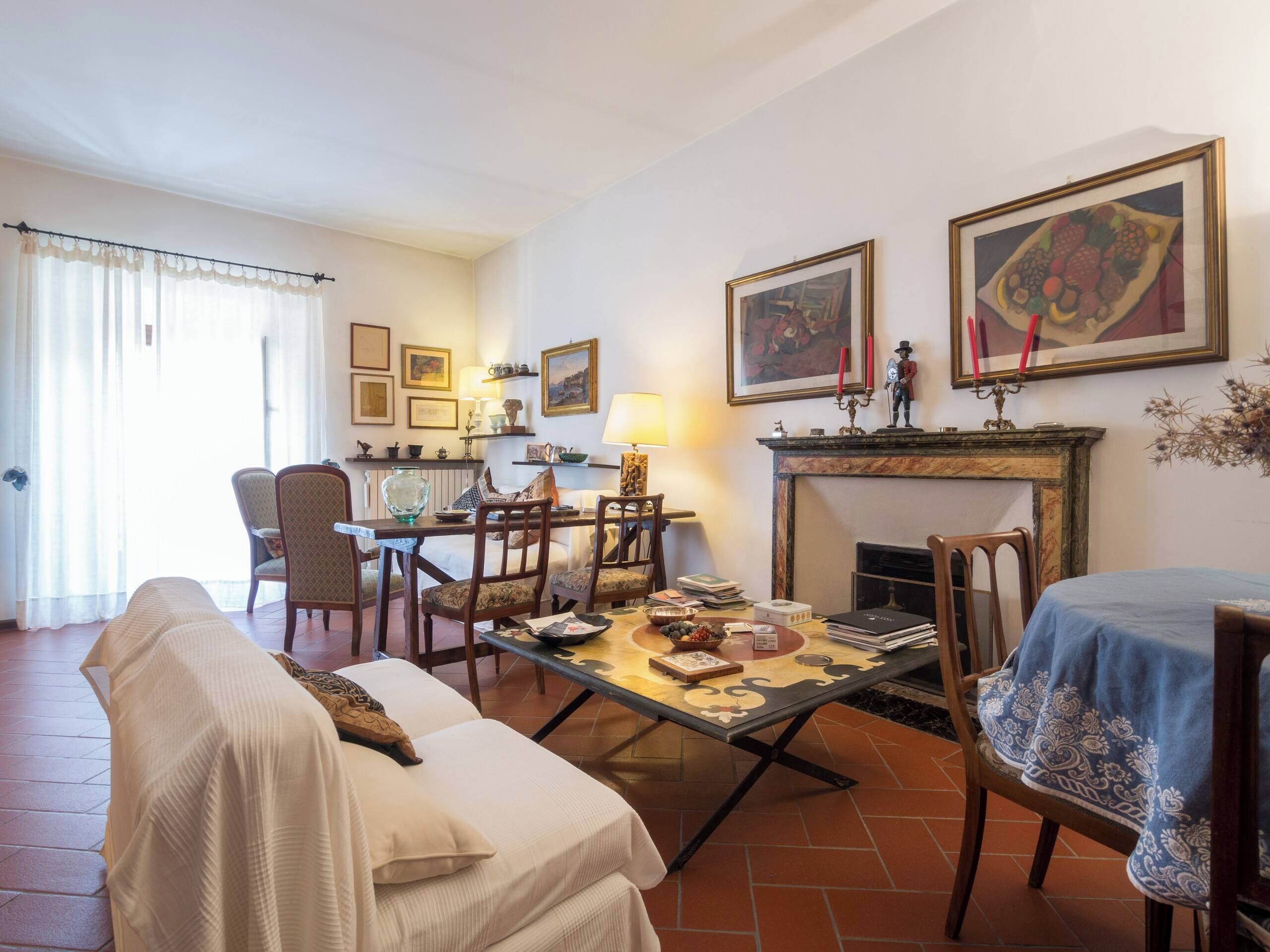 A living room with a sofa, dining table, chairs, a fireplace, and artwork on the walls.