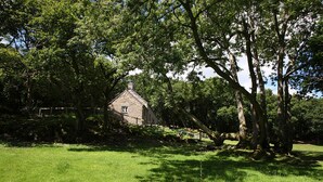 A stone house surrounded by lush green trees and grass. - Tyddyn Derwen, Bodnant Estate, Colwyn Bay, Conwy, Wales (Colwyn Bay)