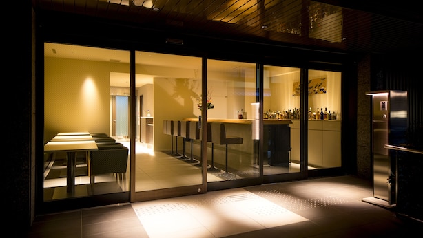 A modern interior with a bar area, seating, and a refrigerator. - My K House (Kyoto)