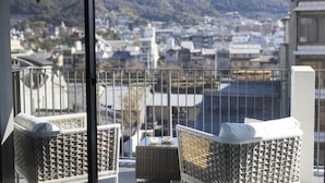 A balcony with wicker furniture and a view of a cityscape and mountains. - My K House (Kyoto)