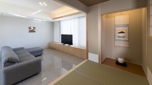 A modern living room with a sectional sofa, a flat-screen TV, and a minimalist design. - My K House (Kyoto)