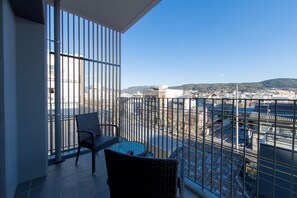 A balcony with a view of a cityscape, a round glass table, and two wicker chairs. - My K House (Kyoto)