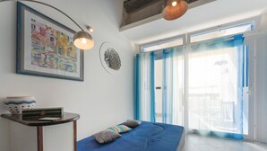 Een slaapkamer met een bed, nachtkastje, een ingelijste foto en een raam met gordijnen.
