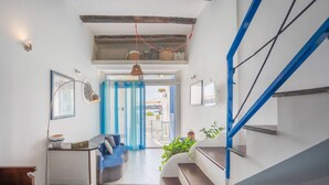 Een modern interieur met een trap, een zithoek met kussens en uitzicht door een deurpost.