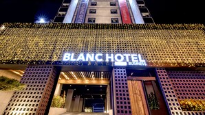 El exterior del Hotel Blanc con su señalización iluminada y luces decorativas.