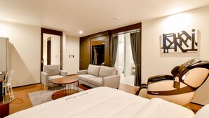Una habitación de hotel con una cama, un sofá, una silla, una mesita y un sillón de masaje.