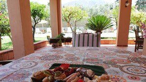 Una mesa con mantel estampado y una bandeja de pasteles y frutas variadas.
