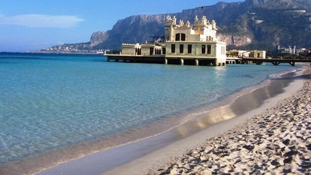 Un hotel frente a la playa con un edificio grande y un muelle que se adentra en el agua.
