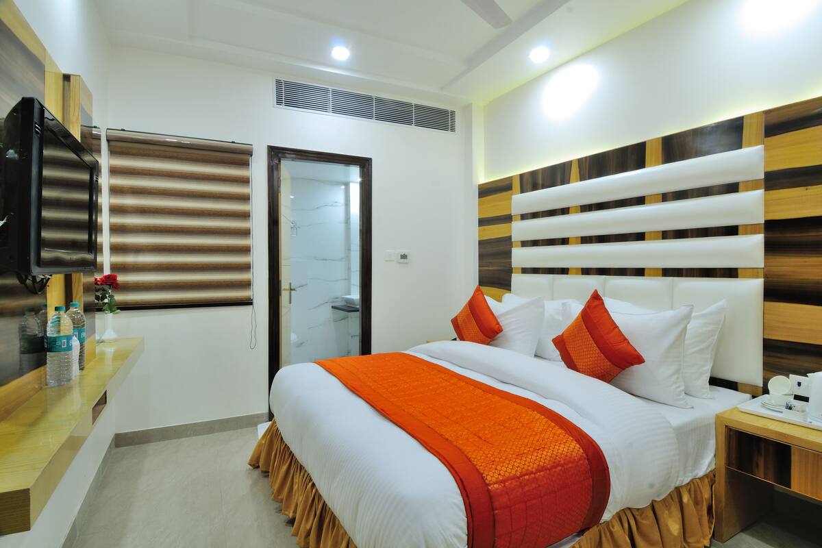 A hotel room with a bed, bedside table, and a TV on the wall.