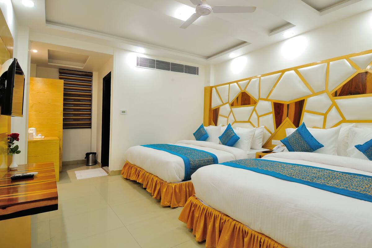 A hotel room with two beds, a ceiling fan, and a small table with a vase of flowers.