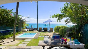 Ein Garten mit Pool, Terrassenmöbeln und Blick aufs Meer.