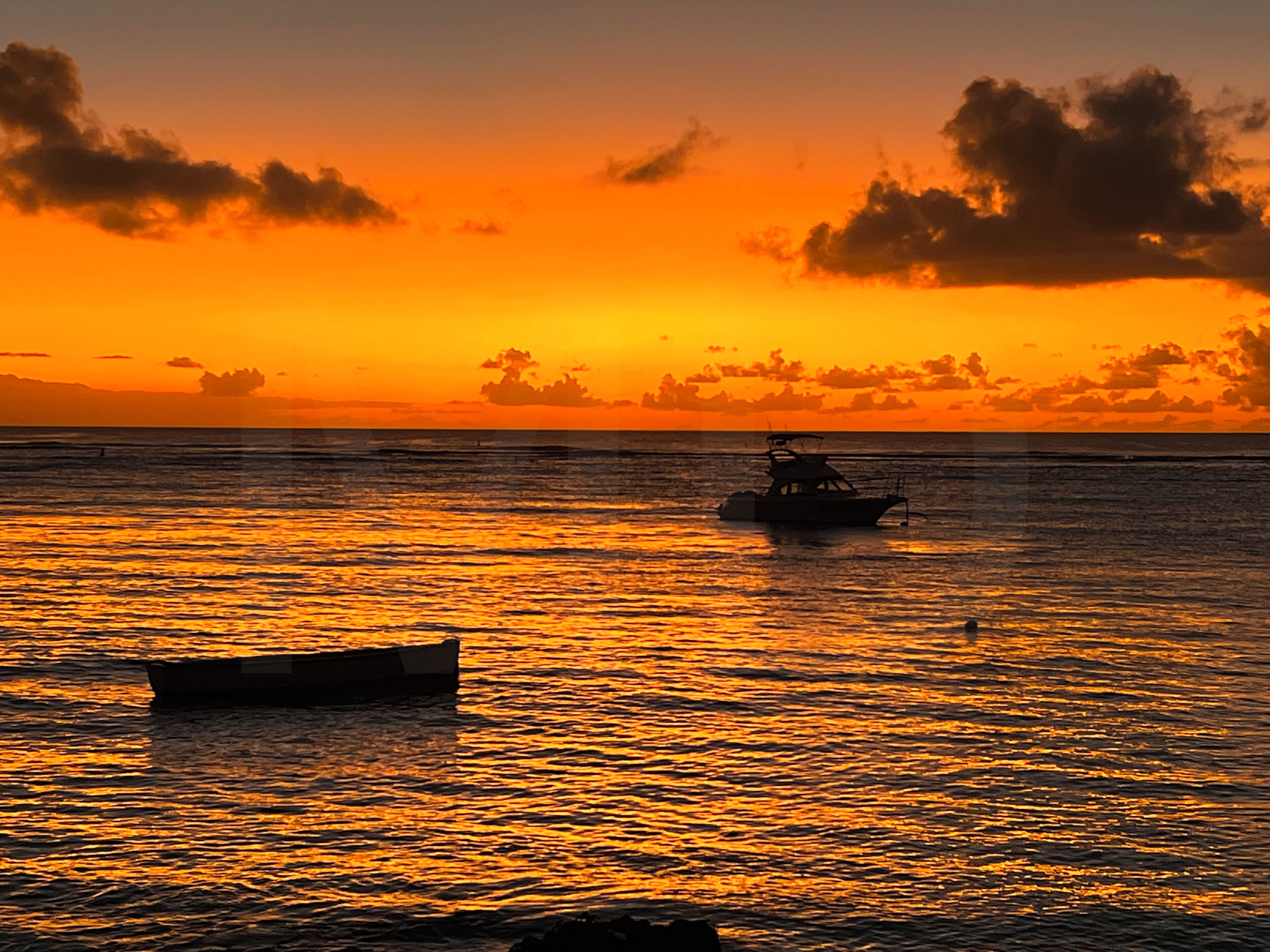 A sunset over a calm sea with boats.