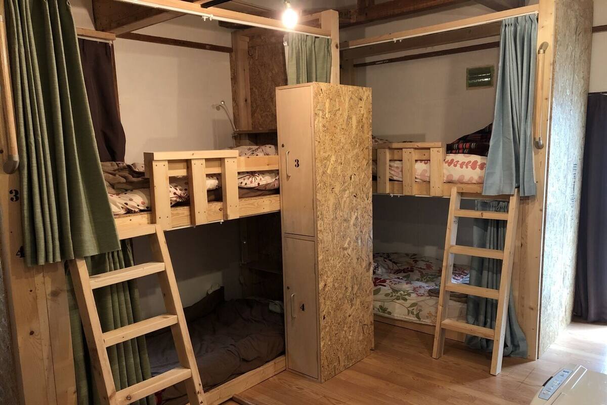 A bunk bed room with a wardrobe, a ladder, and a small desk.