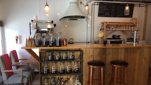 A cozy café with wooden furniture, a coffee machine, and shelves with jars of coffee.