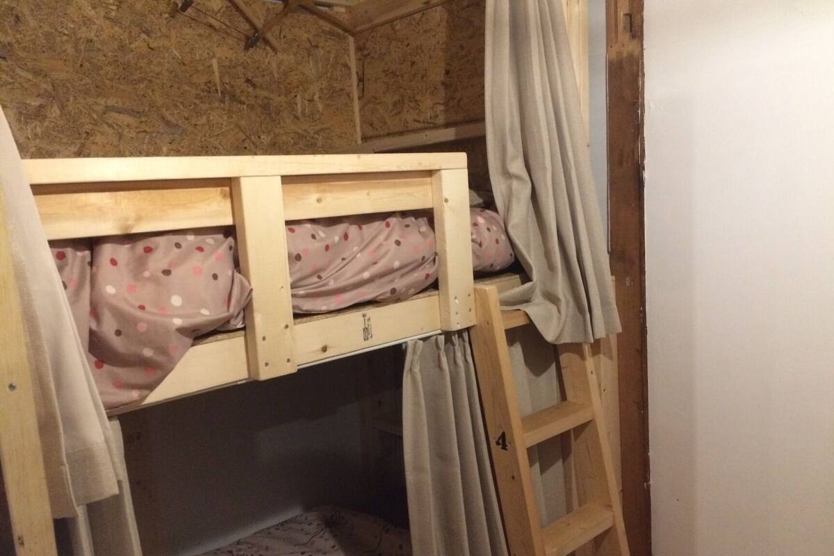A bunk bed with a lower bunk, a wooden headboard, and a curtain.