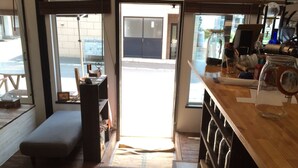A cozy interior with a wooden bench, a small table, and a view of the street through a glass door.